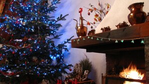 A cozy room with a decorated Christmas tree, a fireplace, and a rustic wooden mantel. - Hotel Splendor (Dimaro Folgarida)