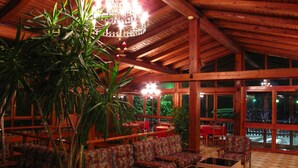 An indoor seating area with wooden beams, patterned sofas, and a large plant. - Hotel Splendor (Dimaro Folgarida)