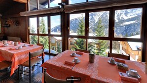 A dining area with tables set for four, large windows offering mountain views, and a wooden interior. - Hotel Splendor (Dimaro Folgarida)