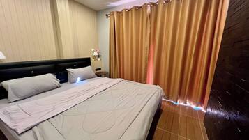 Ein Hotelzimmer mit Bett, Vorhängen, Nachttisch und Wand mit strukturierter Oberfläche.