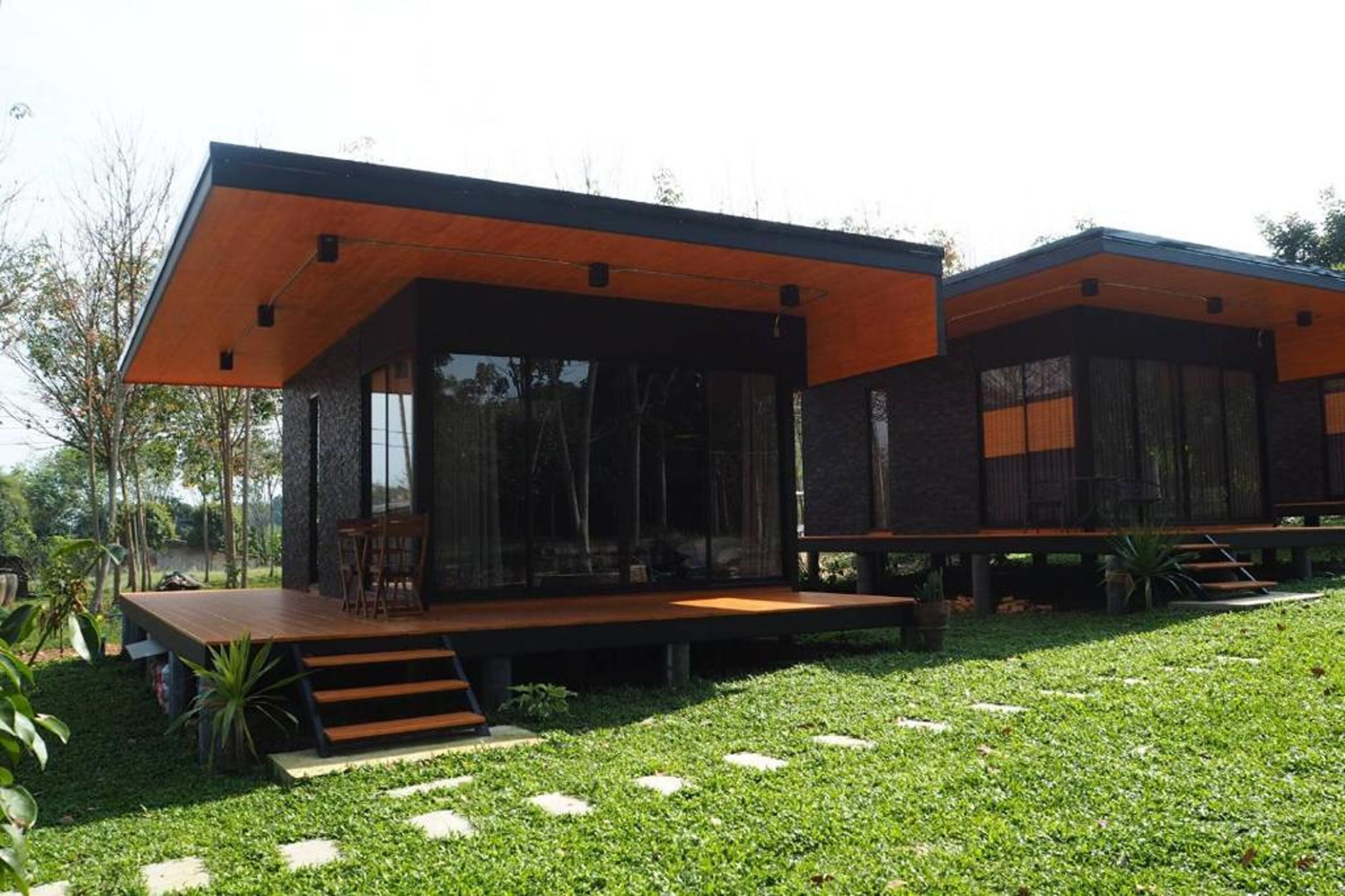 Una casa moderna con terraza de madera y fachada de vidrio.