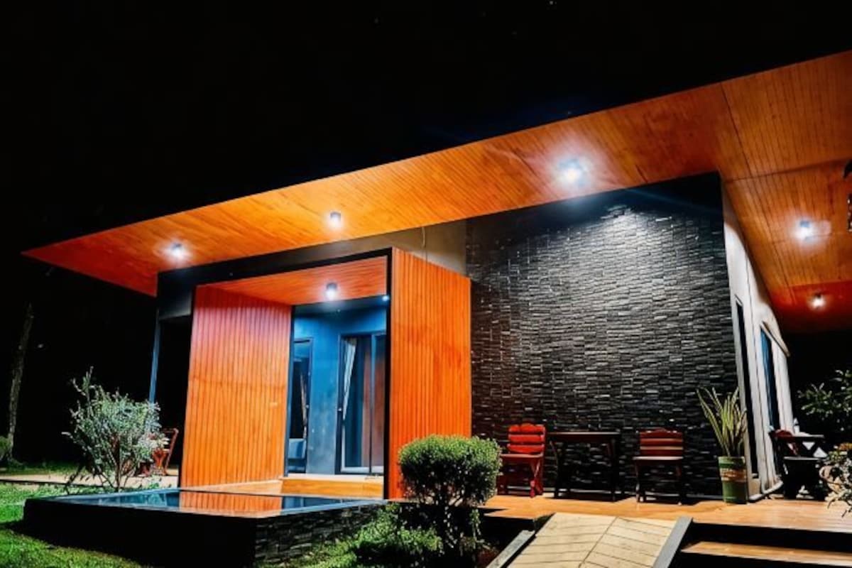 A modern house with a wooden exterior, a stone wall, and a pool.