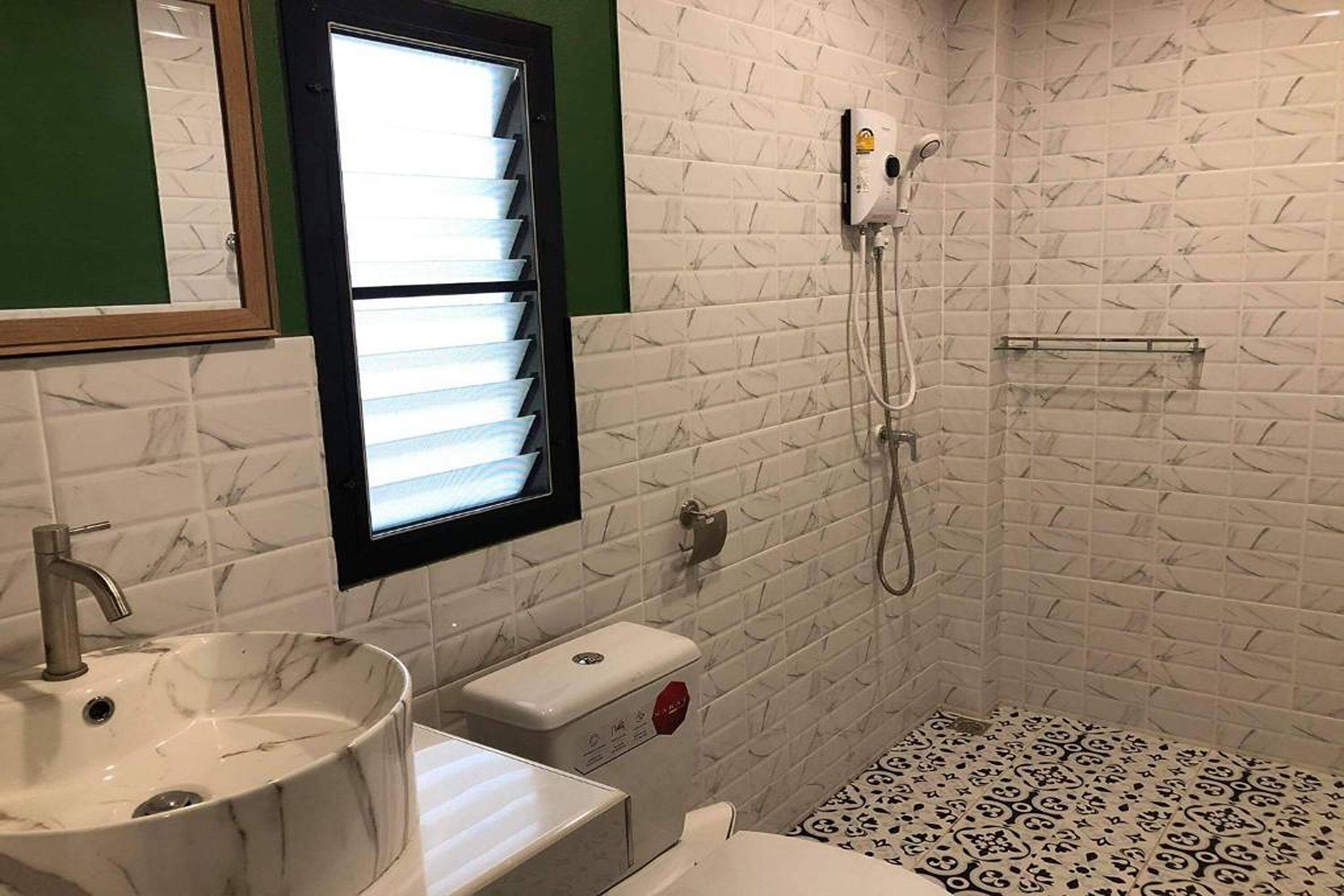 A bathroom with a marble sink, a toilet, and a shower with a handheld showerhead.