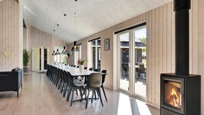 Una larga mesa de comedor con sillas, una chimenea y ventanas amplias.