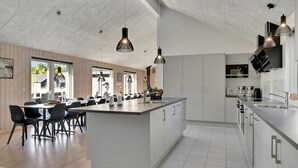 Una cocina moderna con una isla central, electrodomésticos de acero inoxidable e iluminación colgante.