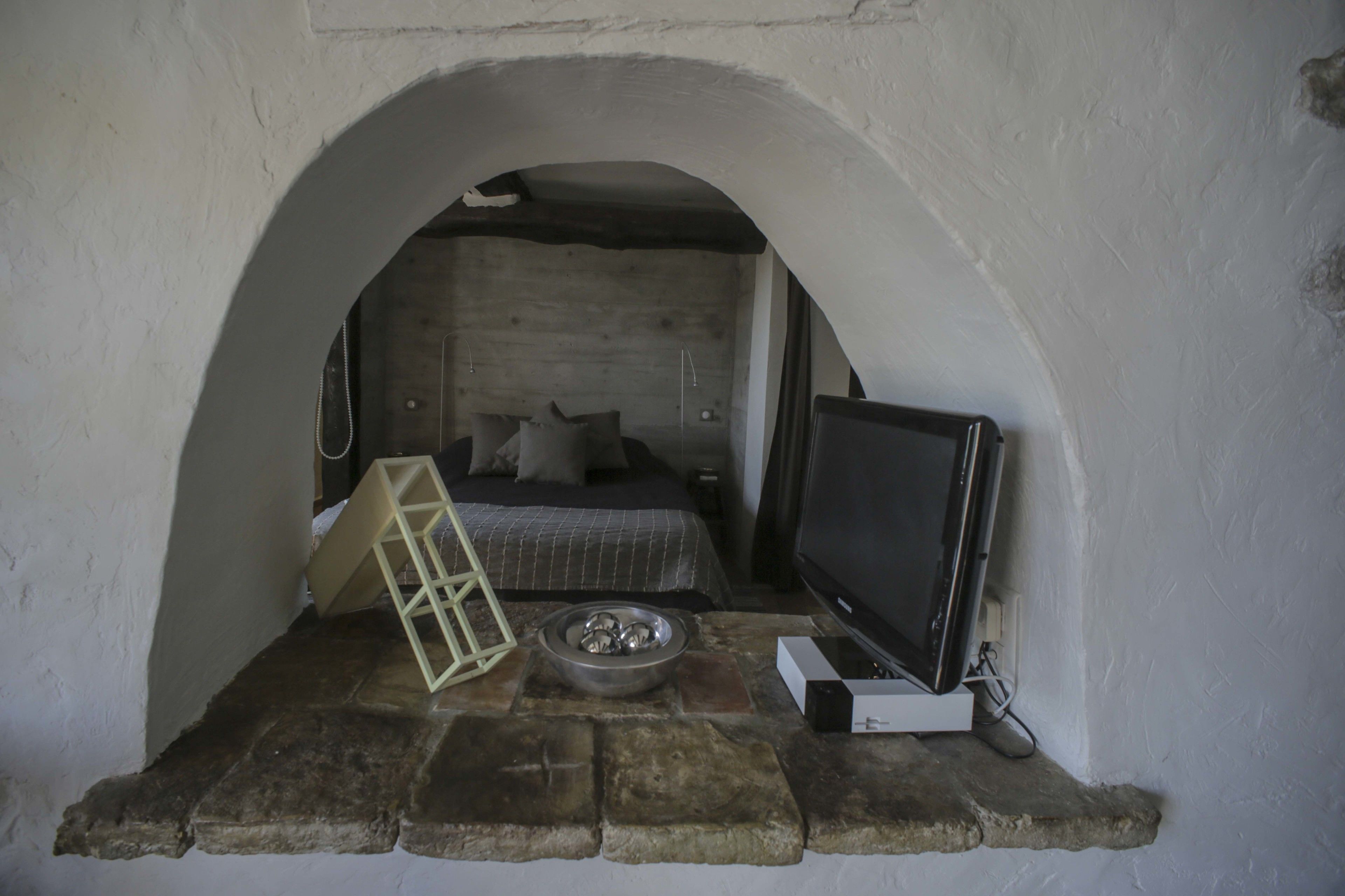 A cozy room with a bed, a television, a small table with a bowl, and a window.