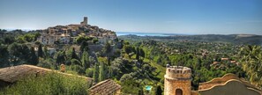 A historic town with a prominent hilltop castle, surrounded by lush greenery and a clear view of the sea. - La Maison Aux Bonsaïs (Saint-Paul-de-Vence)
