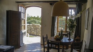 Uma área de refeições com uma mesa redonda, cadeiras, um candeeiro pendente e vista para o exterior.