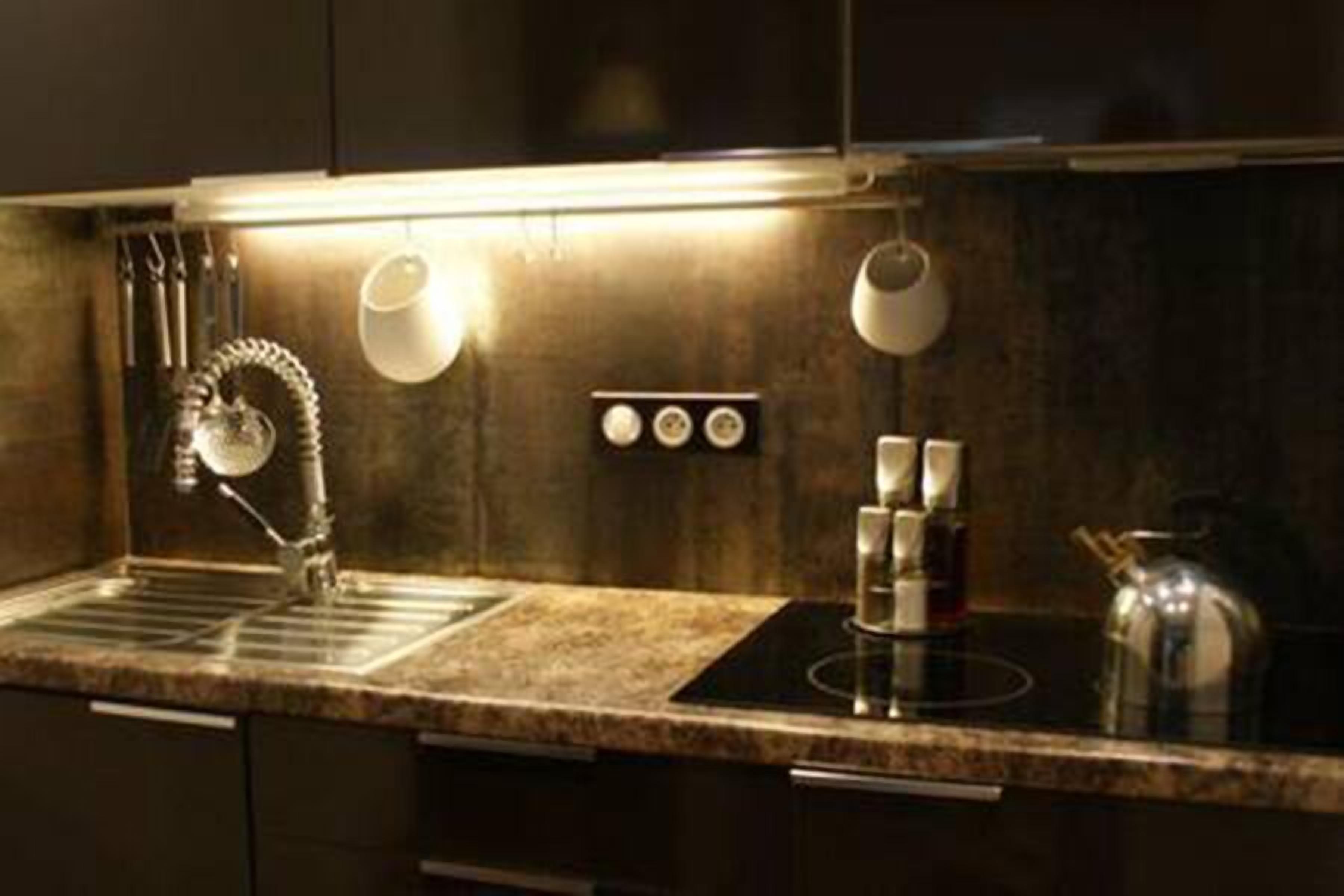 Une cuisine moderne dotée d’un plan de travail en granit, d’appareils électroménagers en acier inoxydable et de luminaires suspendus.