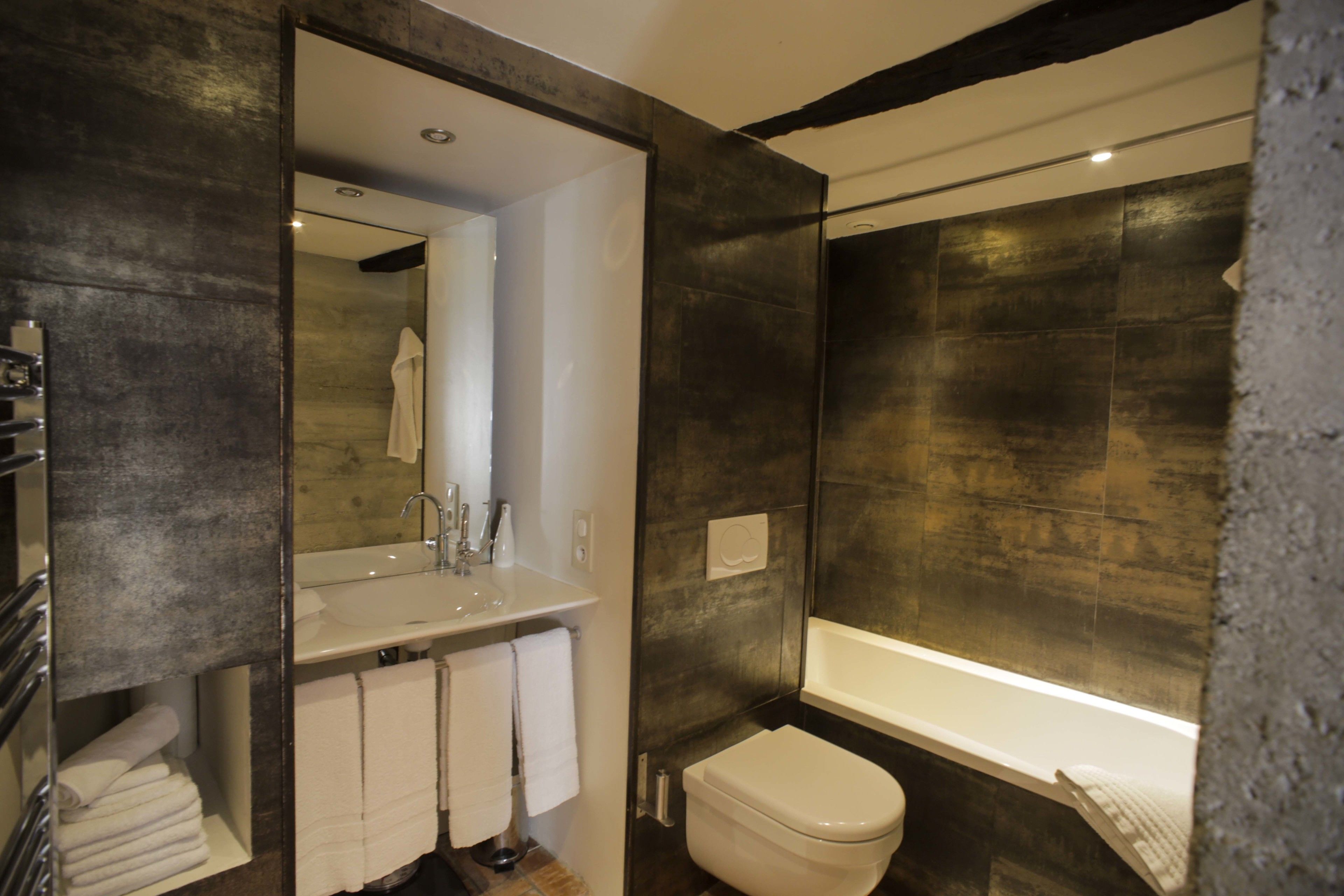 A modern bathroom with a large mirror, a sink, a toilet, and a bathtub.