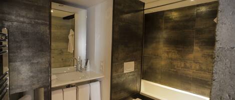A modern bathroom with a large mirror, a sink, a toilet, and a bathtub.