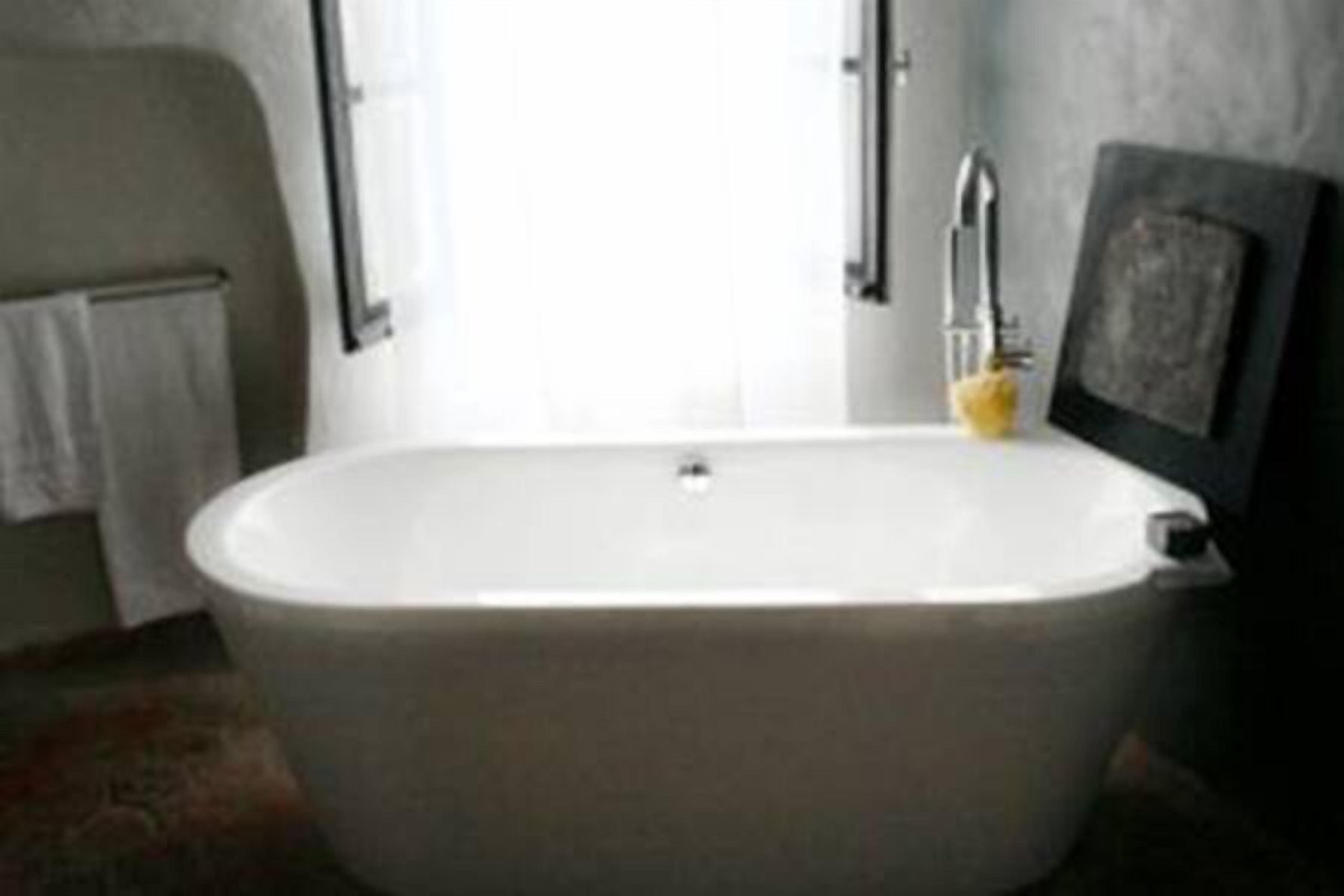A bathroom with a freestanding bathtub, a towel rack, and a framed picture on the wall.