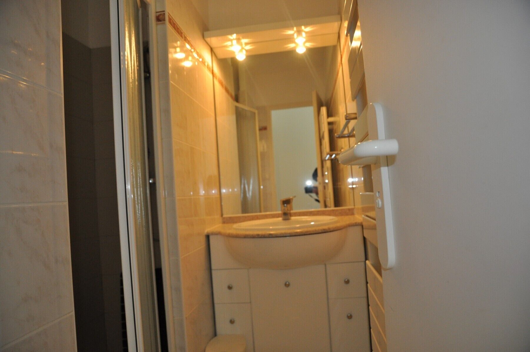 A bathroom with a sink, mirror, and a towel dispenser.