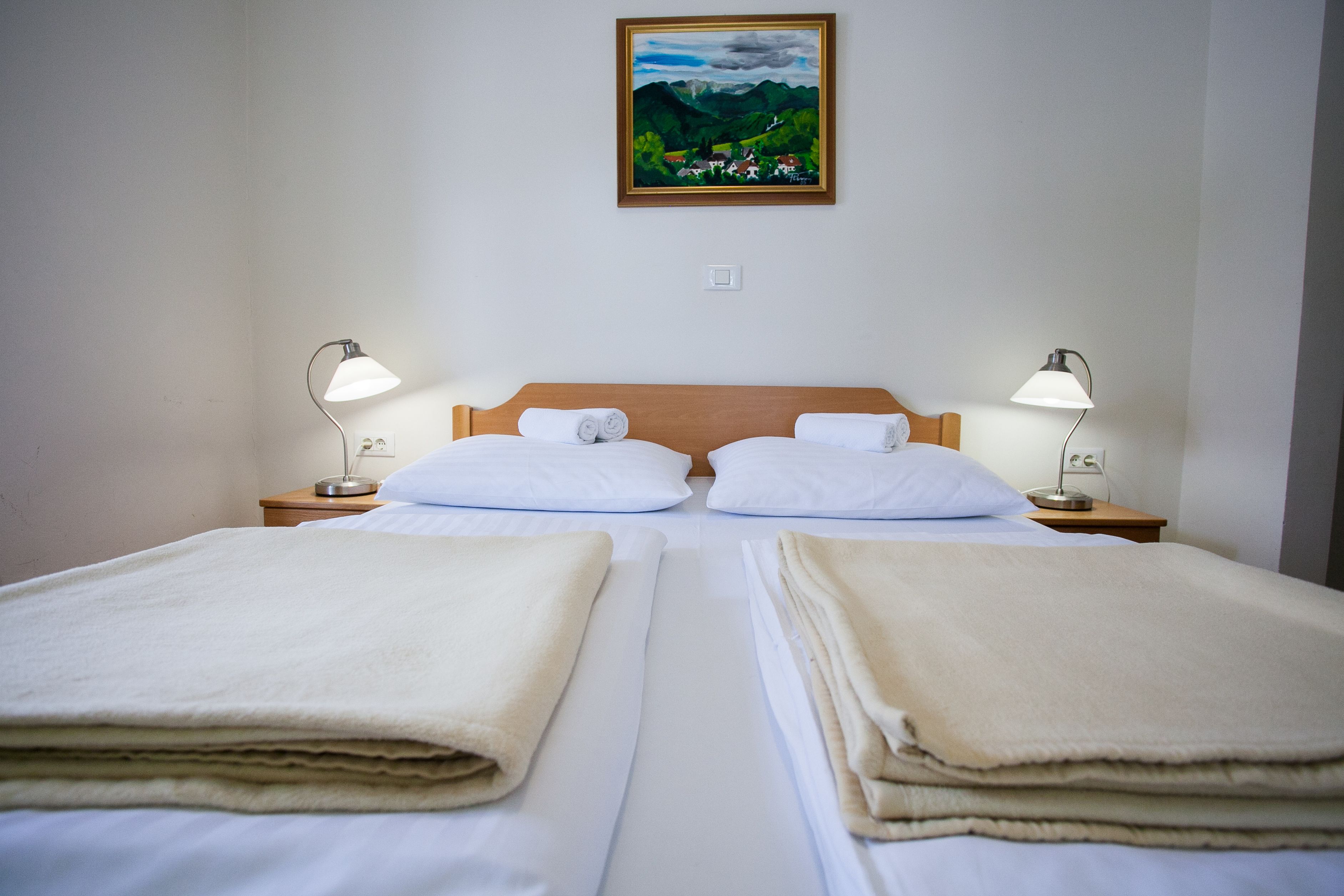 Una cama doble con sábanas blancas y dos lámparas de noche.