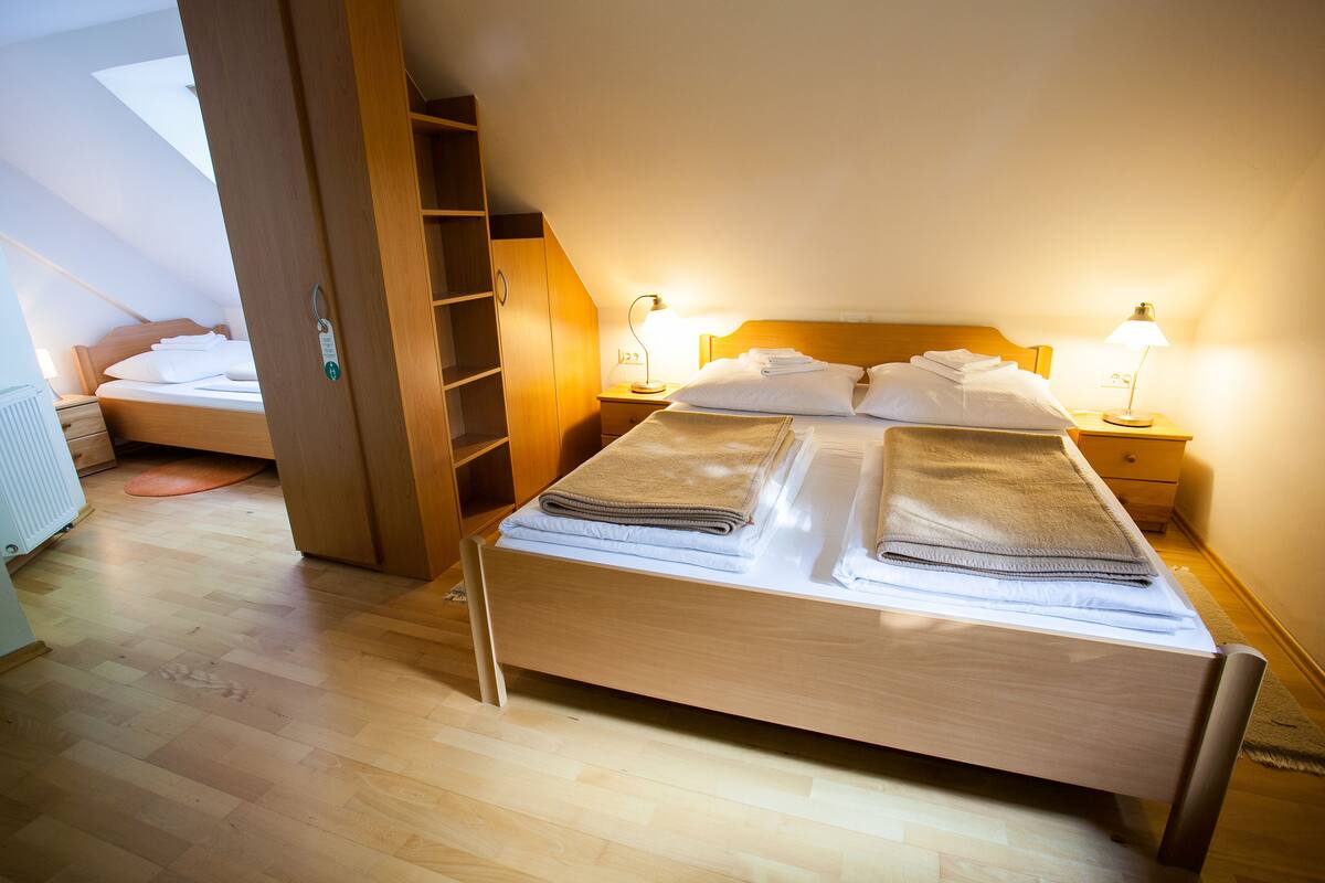 Een opgemaakt bed met handdoeken, een houten hoofdbord en twee bedlampjes.