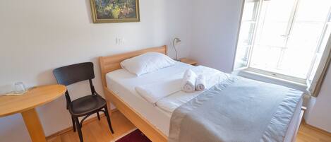 A neatly arranged bedroom with a bed, a chair, a small table, and a window.