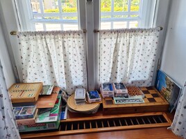 Una habitación con ventana, cortinas y un juego de mesa Monopoly.