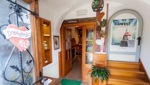 Ein Hotel mit Eingang, einer Holztreppe, einer Rezeption und einem Plakat, das eine Veranstaltung bewirbt.