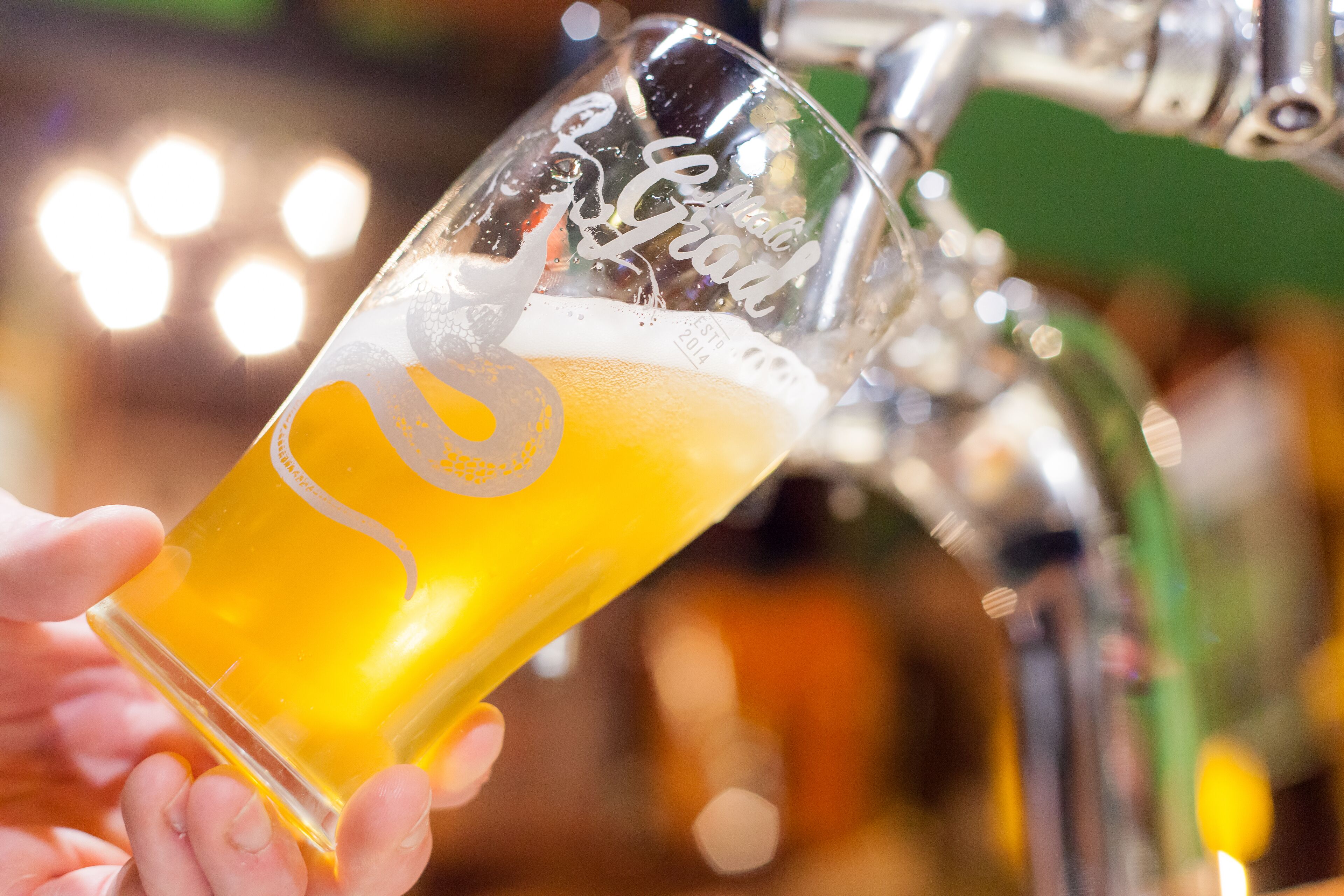 Una mano sosteniendo una jarra de cerveza con un logo y texto.
