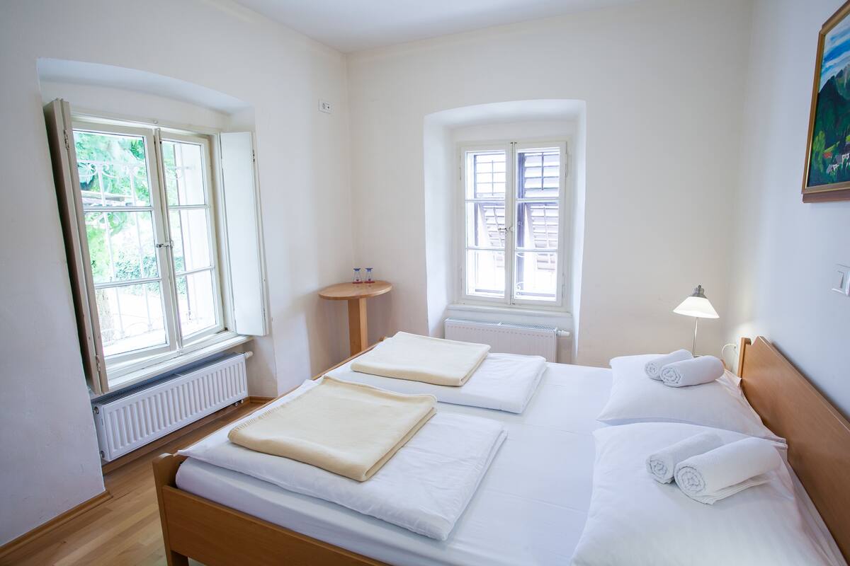 Een hotelkamer met twee bedden, een radiator, een klein tafeltje en een lamp.