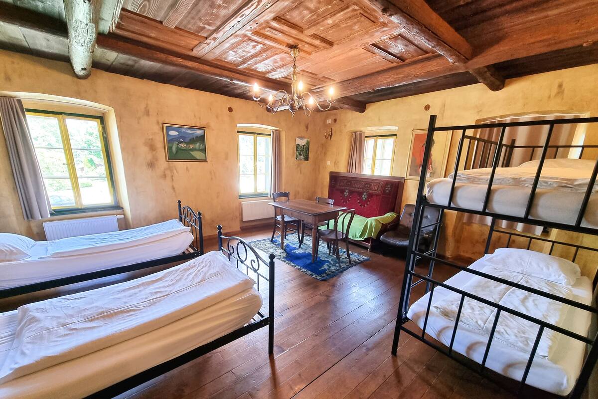 Een rustieke kamer met houten vloeren, stapelbedden, een eettafel en een kroonluchter.