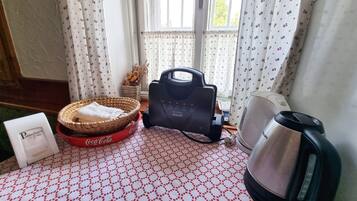 Una habitación con piso estampado, una cesta con una toalla, un electrodoméstico negro, una cafetera y un cartel con texto.