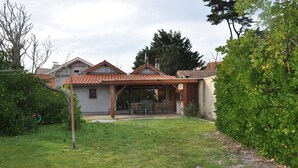 Une maison dotée d’un patio couvert, d’un petit jardin et offrant une vue sur les maisons voisines.