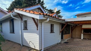 Une maison de plain-pied avec un toit en tuiles, une antenne parabolique et une terrasse en briques.