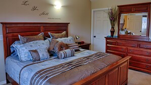 A bedroom with a large wooden bed, multiple pillows, a bedside lamp, and a dresser with a mirror.