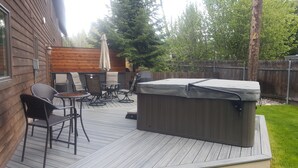 A wooden deck with outdoor furniture, a hot tub, and a wooden fence.