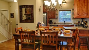 A spacious kitchen with wooden cabinets, a dining table set for six, and a chandelier.
