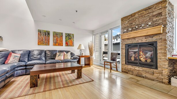 Ein modernes Wohnzimmer mit Kamin aus Stein, einer Ledersofa und Holzboden.