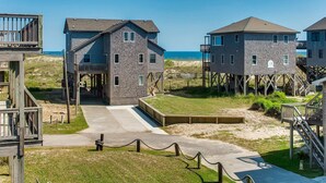 Ein Strandgrundstück mit erhöhten Holzkonstruktionen, einem Betonweg und einer Sandküste.