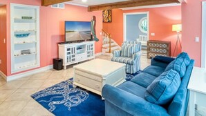 A living room with a blue sofa, a white entertainment unit, and a staircase leading to another level.