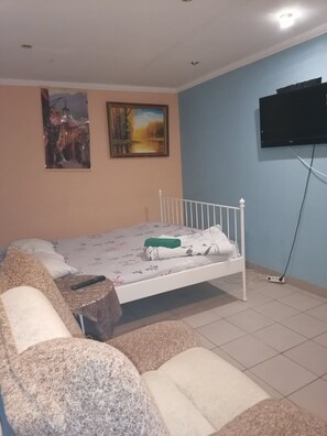 A bedroom with a bed, a TV mounted on the wall, and a sofa. - Snegiri (Perm)