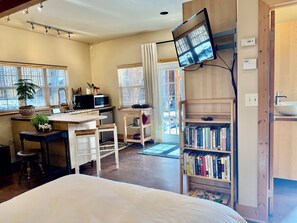 Een kamer met een bed, een bureau met een computer, een boekenkast en een raam met gordijnen.