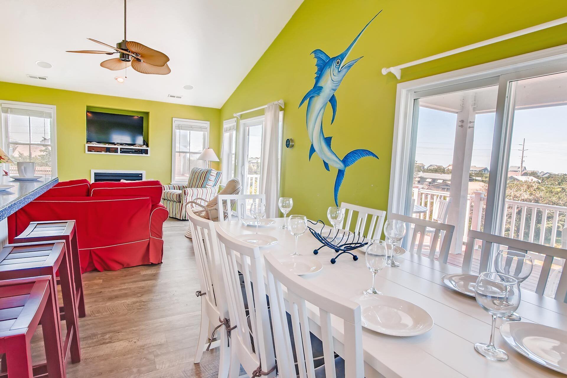 A dining area with a large window, a ceiling fan, and a wall mural of a fish.