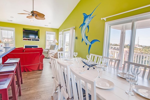 A dining area with a large window, a ceiling fan, and a wall mural of a fish.