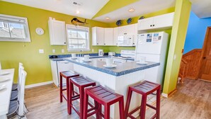Una cocina compacta con armarios blancos, encimera de granito y una isla central con taburetes de bar.