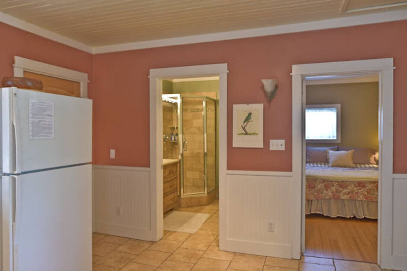 Een kleine kamer met een kitchenette, een douche en een bed.