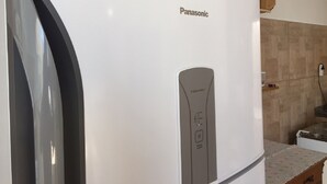 A white Panasonic refrigerator with a freezer control panel and a water dispenser. - Residencial Dois Amores 2 (Florianópolis)
