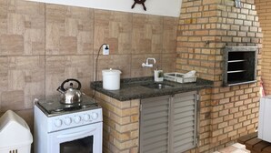 A kitchen with a stove, oven, sink, and a brick oven. - Residencial Dois Amores 2 (Florianópolis)