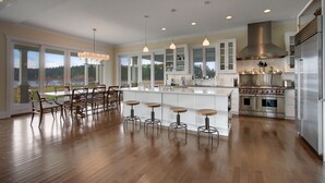 A spacious kitchen with a large island, bar stools, and a view of the outdoors.