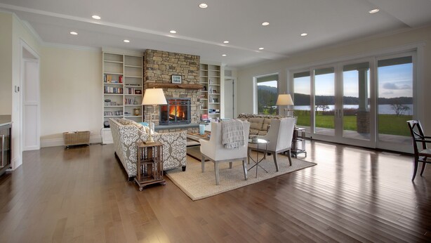 A spacious living room with a fireplace, large windows, and a view of the outdoors.