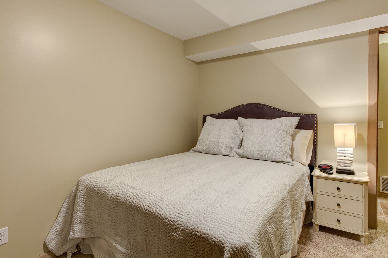Un dormitorio con cama, mesita de noche y lámpara.