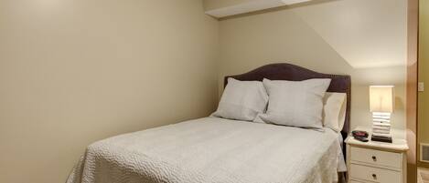 Un dormitorio con cama, mesita de noche y lámpara.
