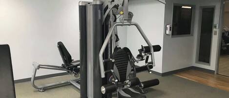 A gym with a squat rack, bench press, and various weight machines.