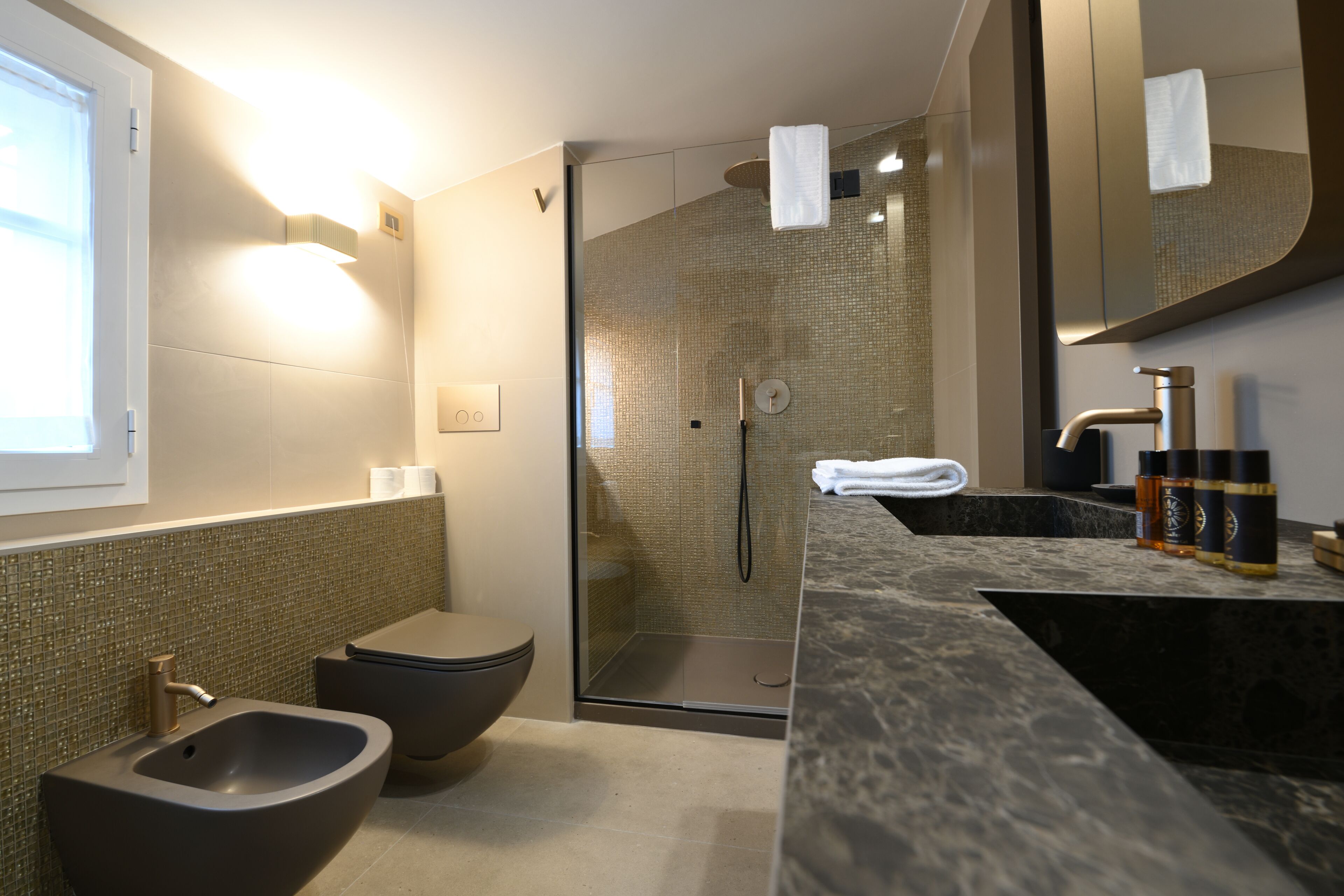 A modern bathroom with a bidet, toilet, and glass-enclosed shower.