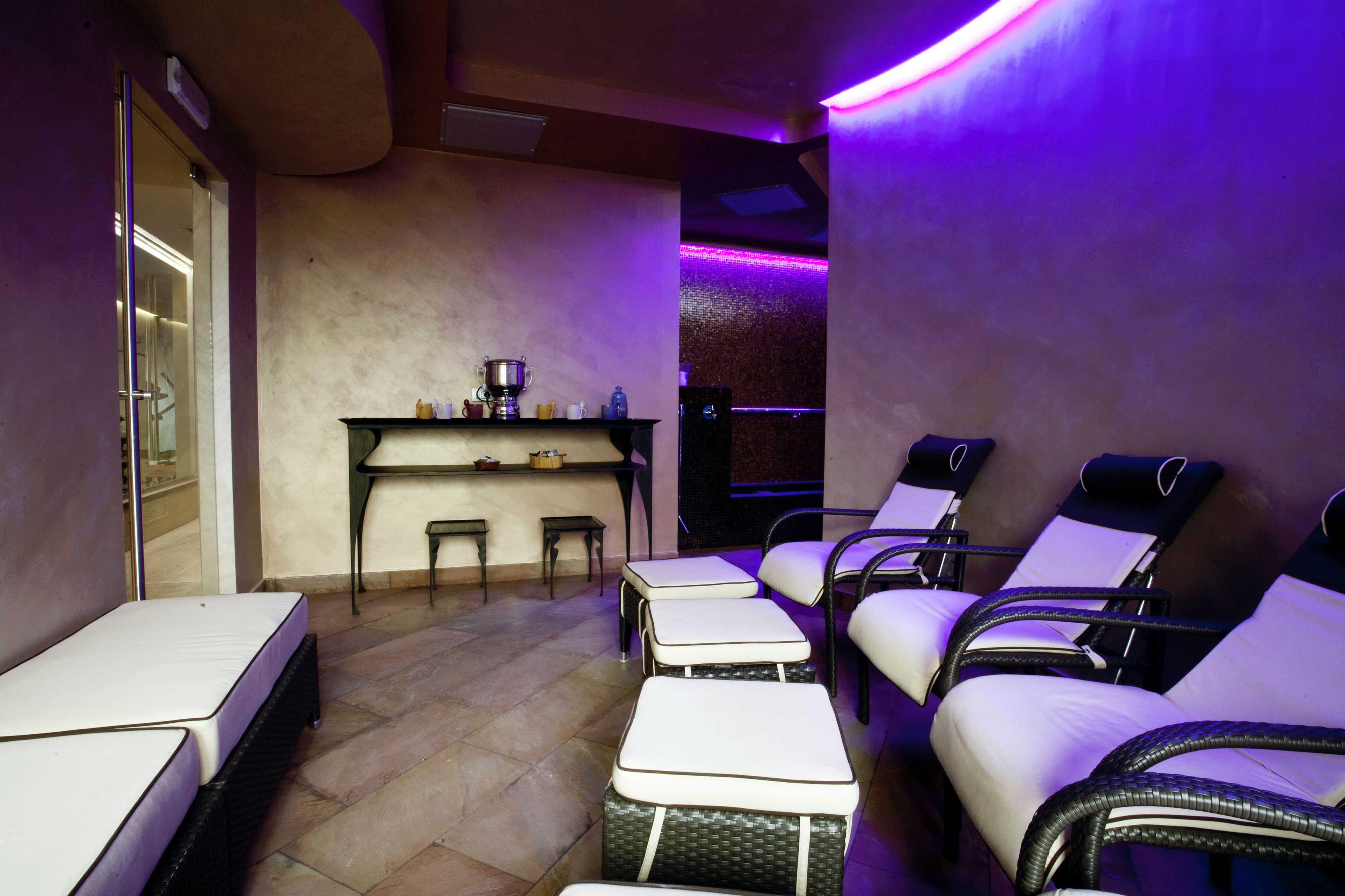 A room with a massage table, a small bar area, and several reclining chairs.