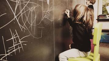 A person sitting on a green chair writing on a blackboard.